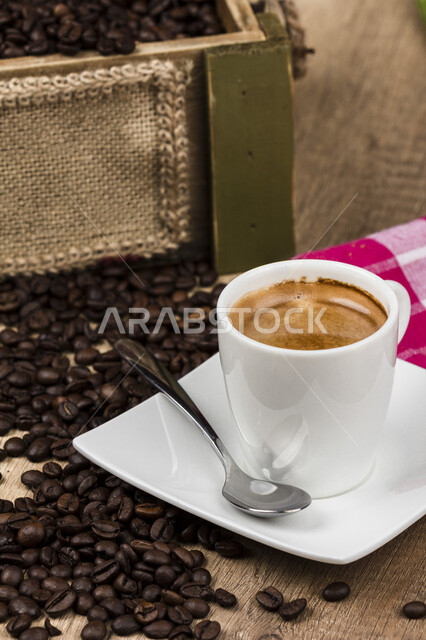 فنجان قهوة سوداء, قهوة اسبرسو داكنه, حبوب البن المتناثره .