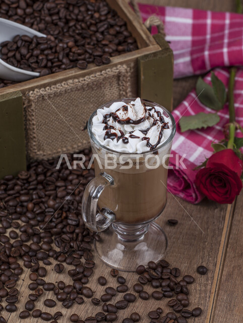 كوب من الكابتشينو المملوء بالكريما المزينة بالشوكلاته، حبات البن المتناثرة، مشروب الكابتشينو الساخن.