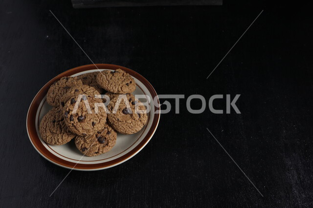 طبق من رقائق الكوكيز المقرمش، رقاقات البسكويت الهشة، كوكيز، حلويات مخبوزة طازجة، خلفية سوداء