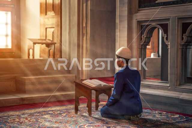 ولد صغير عربي خليجي  في أحد المساجد العربية ، يقرأ المصحف الشريف  ، تلاوة القرآن الكريم ، تحفيظ القرآن الكريم للأطفال ، العبادة والتقرب الى الله ، أماكن إسلامية مقدسة ، إسلاميات وعبادة .