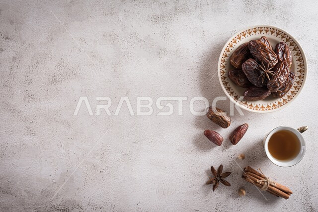 طبق من حبات التمر الصحي مع كأس من الشاي ، تمر مجدول ، وجبة ذات قيمة غذائية عالية ، ضيافة رمضانية ،  وجبة فطور صحية ، خلفية بيضاء .