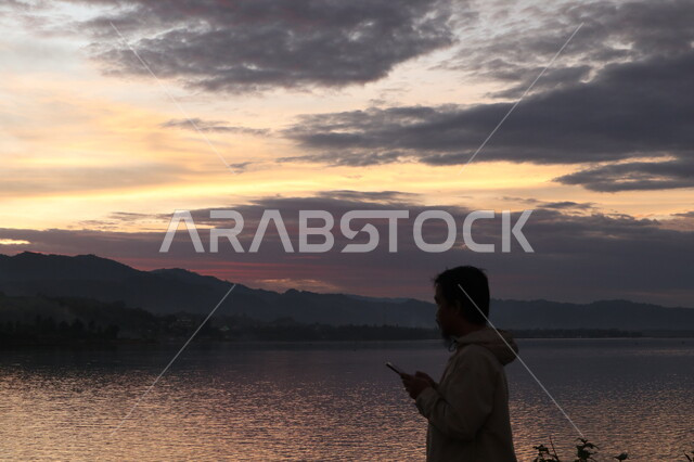 صورة ظلية من الخلف لرجل يقف امام بحيره مائية , مناظر طبيعية , الاسترخاء والتأمل , منظر غروب الشمس , خلفية الطبيعة , سوليليت .