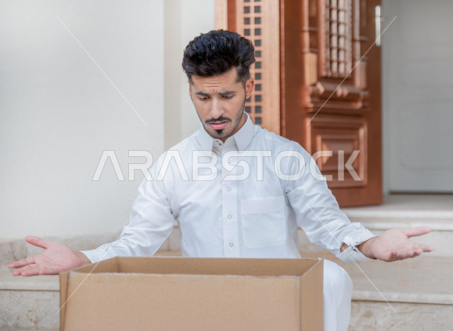 شاب عربي سعودي خليجي يقوم بفتح الطلبية  ،ايماءات وجه ويدين تدل على الدهشة والصدمة ، عمليه توصيل صناديق الطلبات الخاصة بالزبائن ، خدمات الشحن و التوصيل ذات الجودة العالية