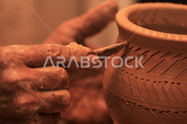 صوره مقربه ليد رجل يقوم بتزيين جرة من الطين,  أواني فخاريه شعبيه, تراثيات وشعبيات, أواني خزفيه مزخرفه مصنوعه من الطين, شعبيات سعوديه