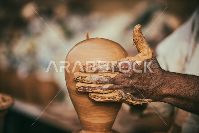 صوره مقربه ليد رجل يقوم بصناعة جرة من الطين, أواني فخاريه شعبيه, تراثيات وشعبيات, أواني خزفيه  مصنوعه من الطين, شعبيات سعوديه