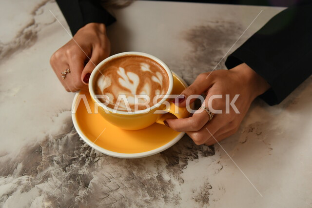 صورة مقربه ليدين إمرأه تمسك بفنجان القهوة برغوة كثيفة ، مشروب الكابتشينو الساخن ، مشروبات ساخنة لذيذة ، فنجان القهوة الساخن, خلفية رمادية .