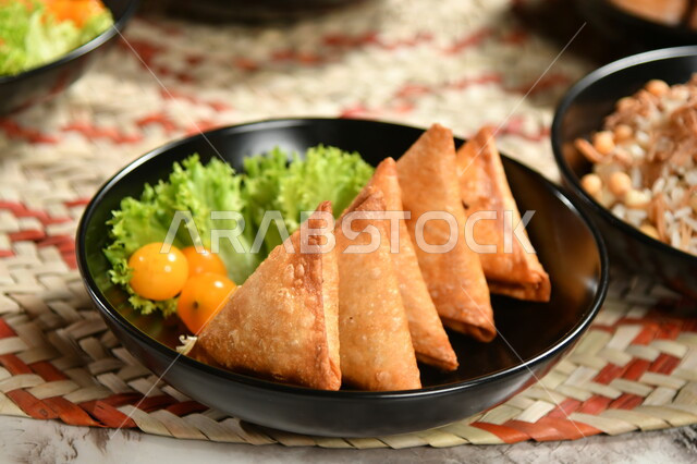 صورة مقربة لطبق السمبوسك, وجبة افطار بأصناف من المأكولات العربية السعودية اللذيذة الرمضانية على طاولة الطعام ، اجواء رمضانية ،  شهر رمضان ، رمضان كريم