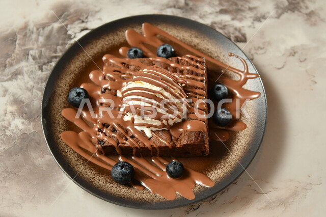 A plate of chocolate cake dessert decorated with a piece of ice cream decorated with chocolate with vanilla flavor, oriental sweets, sweets and sugars, delicious candy pieces, dessert, delicious cold sweets, gray background