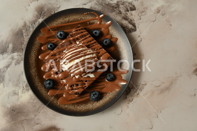 صورة من الاعلى لطبق من حلا كيك الشوكولاته المزينة بقطعة آيس كريم مزينة بالشوكولاته بنكهة الفانيليا ، حلا شرقي ، حلويات وسكريات ، قطع الحلوى الشهية ، التحلاية ، حلويات باردة لذيذة ، خلفية رمادية