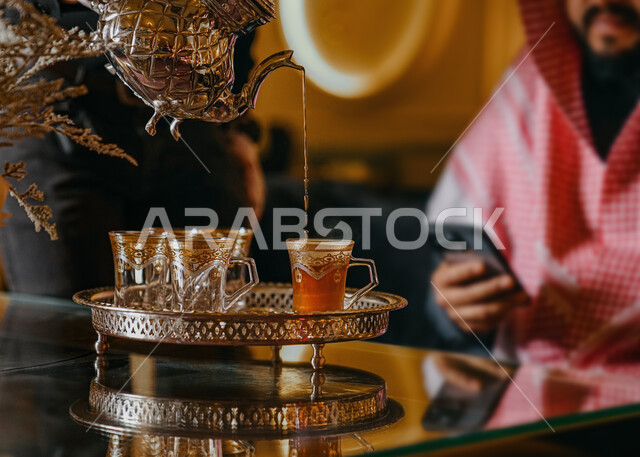 صورة مقربة لإبريق معدني وكؤوس ,  تقديم الشاي بالطريقة السعودية ، حسن الضيافة والإستقبال، قضاء أوقات ممتعة ، جلسة وناسة واجتماعات   ،  زيارات الأهل والأقارب  , مشروبات ساخنة .