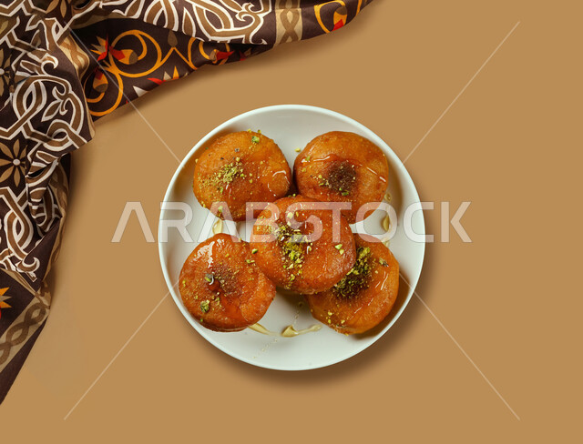 A dish of sweet luqaimat, sweets and sugars, dessert dumplings, oriental dessert, dessert recipes and dishes, restaurants for oriental Arabic food, brown background