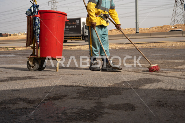 صورة مقربة لعامل النظافة أثناء فترة العمل  وإزالة النفايات والقمامة من الطريق ،  تنظيف الأبنية و الطرقات و الأرصفة ، الاهتمام بنظافة البيئة ، بلدية مدينة الرياض.