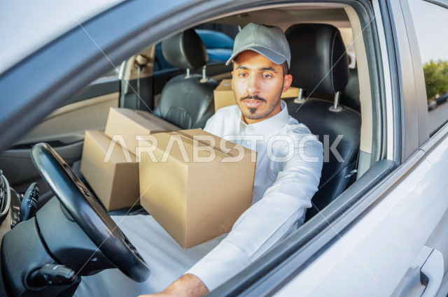 A young Saudi Arab Gulf man sitting in a car with delivery parcels, the process of delivering orders to customers, shopping and ordering products online, high-quality shipping and delivery services