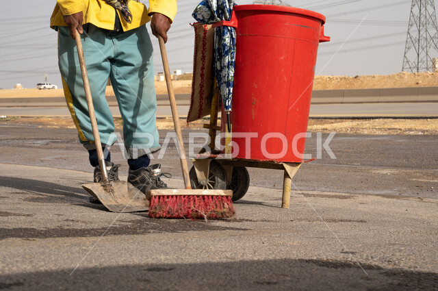 Close-up of a cleaning worker in work clothes cleaning roads and sidewalks, cleaning cart, cleaning tools for work, caring for the cleanliness of the environment.