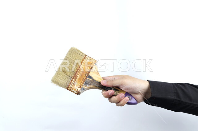 صورة مقربة ليد تمسك فرشاه دهان  , فراشي و ادوات طلاء , رسم وفنون , مهن وحرف يدوية  , خلفية بيضاء .