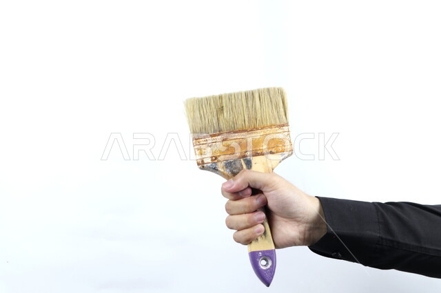 Close-up of a hand holding a paintbrush, brushes and painting tools, drawing and arts, crafts and crafts, white background