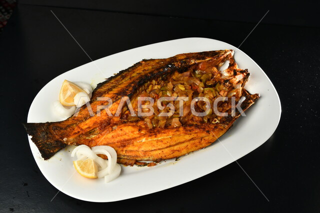 .A dish of marinated fried fish with vegetables, Arabic seafood, a healthy nutritional meal, oriental dishes and recipes , black background