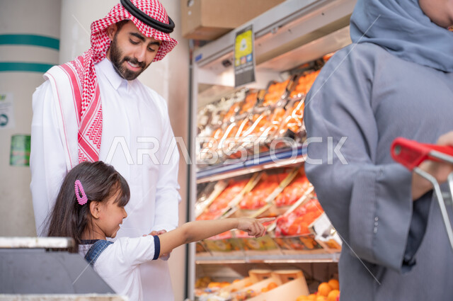 عائلة عربية سعودية خليجية  في قسم الفواكه والخضروات  داخل السوبرماركت ، عربة التسوق ، مستلزمات المستهلك ، السلع والمواد الغذائية ، شراء الاحتياجات المنزلية.