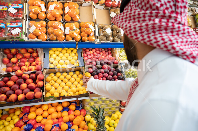 صورة مقربة لرجل عربي سعودي خليجي في قسم الخضراوات والفواكه داخل السوبرماركت   ، الاحتياجات المنزلية ، السلع والمواد الغذائية.