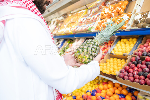  رجل عربي سعودي خليجي في قسم الفواكه داخل السوبرماركت ، الاحتياجات المنزلية ، السلع والمواد الغذائية ، متعة التسوق ، مستلزمات المستهلك.