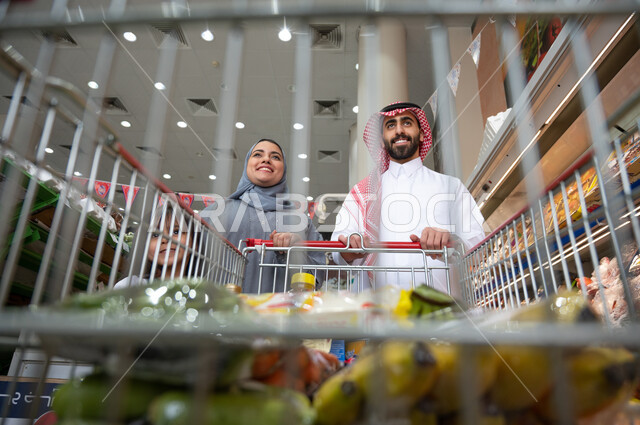 عائلة عربية سعودية خليجية داخل السوبرماركت شراء المواد الغذائية اللازمة   ، شراء الاحتياجات المنزلية ، سلة التسوق الشرائية .