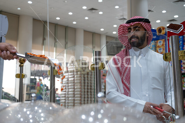 An Arab, Saudi, Gulf man in the nuts section of the supermarket, healthy nuts, a snack, various commodities and foodstuffs, consumer supplies