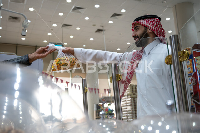 رجل عربي سعودي خليجي  في متجر  المكسرات داخل السوبرماركت  ، مكسرات صحية  ، وجبة خفيفة ، السلع والمواد الغذائية المختلفة ، مستلزمات المستهلك.
