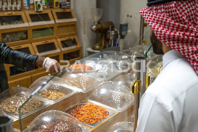 رجل عربي سعودي خليجي  في المتجر يشتري المكسرات   ، وجبة خفيفة ، السلع والمواد الغذائية المختلفة ، مستلزمات المستهلك.