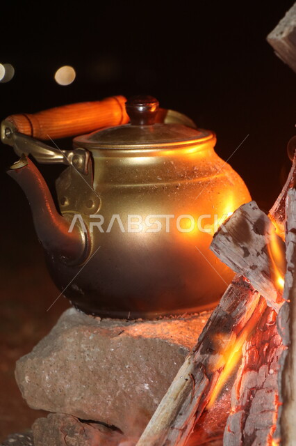 صورة مقربة لإبريق الشاي بجانب الحطب المشتعل، رحلات برية، جلسة بر عربية شعبية، براد شاي على الحطب، شبة نار