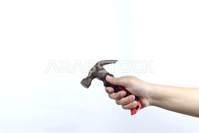 صورة مقربة ليد رجل يمسك بمطرقة معدنية، مقبض بلاستيكي، شاكوش، ادوات البناء، خلفية بيضاء