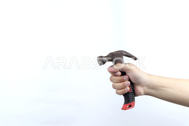 صورة مقربة ليد رجل يمسك بشاكوش معدنية، ادوات البناء، مقبض بلاستيكي، مطرقة حديد، خلفية بيضاء