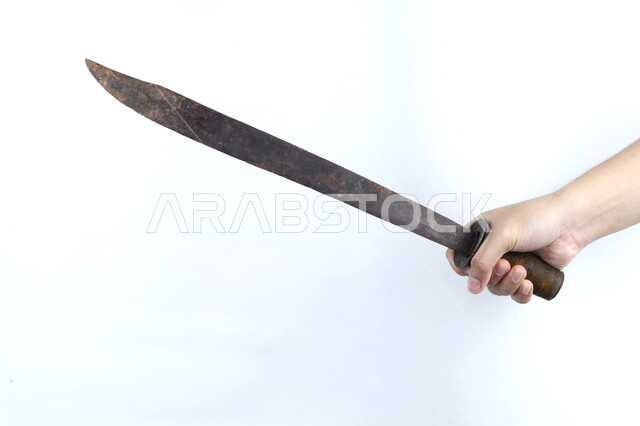 صورة مقربة ليد رجل يمسك سيف صدئ، منجل قديم، ساطور معدني، سيف صدئ، مقبض خشبي، اسلحة قديمة، خلفية بيضاء