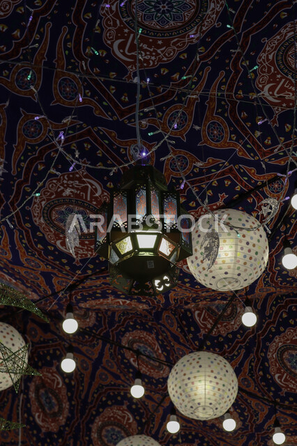 انوار الزينة الرمضانية المعلقة في الشوارع ليلا، فوانيس رمضان، مصابيح مضيئة، احبال الانارة، زينة رمضان، مصابيح معدنية، اجواء رمضانية