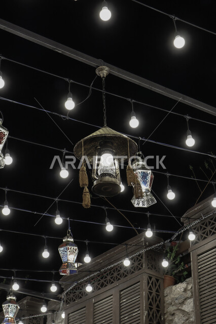 انوار الزينة الرمضانية المعلقة في الشوارع ليلا، مصابيح مضيئة، احبال الانارة، فوانيس رمضان، زينة رمضان، مصابيح معدنية، اجواء رمضانية