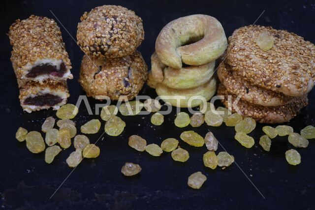 صورة مقربة لمعجنات العيد المحشوة بالتمر، معجنات مشكلة، الحلويات الشعبية الهشة، كعك العيد اللذيذ، مخبوزات طازجة، حلويات طازجة، معجنات مزينة بالسمسم