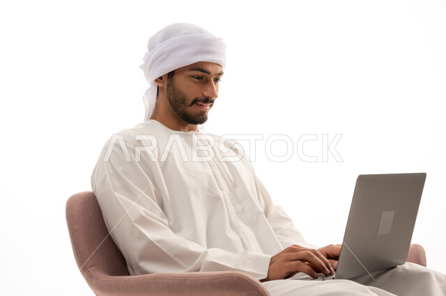 بورتريه لرجل عربي خليجي إماراتي يجلس على كرسي يستخدم جهاز الحاسوب،  تواصل اجتماعي، اجراء مكالمات فيديو، محادثات ودردشة، التواصل مع الأصدقاء، اجتماع عمل عن بعد،  تصفح الانترنت ، خلفية بيضاء .