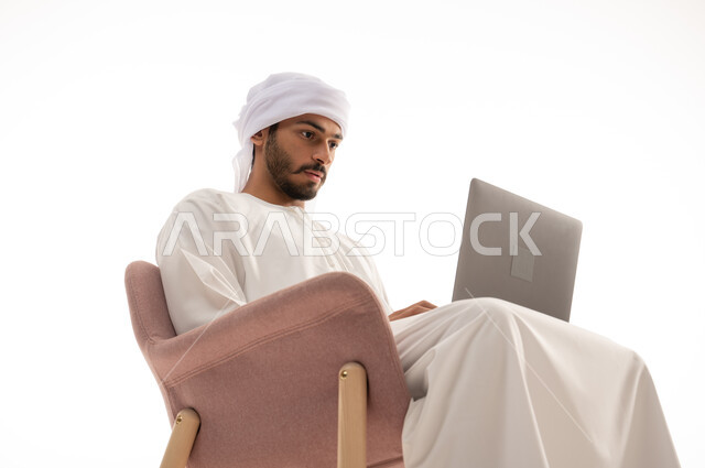 بورتريه لرجل عربي خليجي إماراتي يجلس على كرسي , استخدم جهاز الحاسوب، تصفح الانترنت ، اجراء مكالمات فيديو، تواصل اجتماعي، محادثات ودردشة، التواصل مع الأصدقاء، اجتماع عمل عن بعد،  خلفية بيضاء .