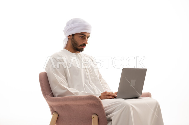 بورتريه لرجل عربي خليجي إماراتي يجلس على كرسي , استخدم جهاز الحاسوب، إجراء مكالمات فيديو، تواصل اجتماعي، محادثات ودردشة، التواصل مع الأصدقاء، اجتماع عمل عن بعد،  تصفح الانترنت ، خلفية بيضاء .