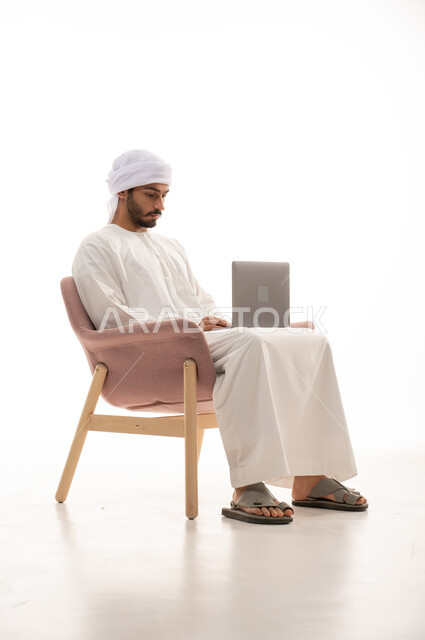 بورتريه لرجل عربي خليجي إماراتي يجلس على كرسي , استخدم جهاز الحاسوب، التواصل مع الأصدقاء،  اجراء مكالمات فيديو، تواصل اجتماعي، محادثات ودردشة، اجتماع عمل عن بعد،  تصفح الانترنت ، خلفية بيضاء .