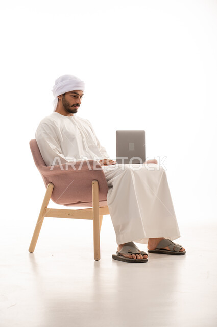 بورتريه لرجل عربي خليجي إماراتي يجلس على كرسي , استخدم جهاز الحاسوب، اجتماع عمل عن بعد، اجراء مكالمات فيديو، تواصل اجتماعي، محادثات ودردشة، التواصل مع الأصدقاء،  تصفح الانترنت ، خلفية بيضاء .