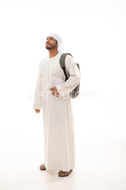 بورتريه لطالب جامعي عربي خليجي اماراتي بالزي الاماراتي التقليدي يحمل حقيبة على ظهره , الذهاب للجامعه ، مفهوم التعليم الجامعي , القراءة والثقافة ,  صورة الجسم بالطول الكامل , خلفية بيضاء