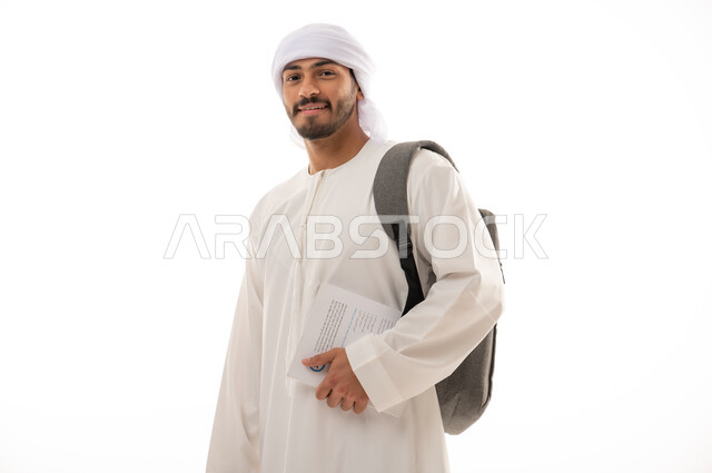 بورتريه لطالب جامعي عربي خليجي اماراتي بالزي الاماراتي التقليدي يحمل حقيبة على ظهره , الذهاب للجامعه ، مفهوم التعليم الجامعي , القراءة والثقافة ,  خلفية بيضاء
