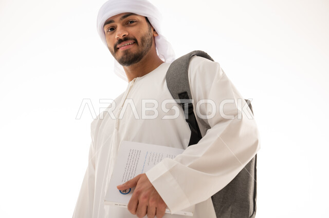 بورتريه لطالب جامعي عربي خليجي اماراتي بالزي الاماراتي التقليدي يحمل حقيبة على ظهره ,  مفهوم التعليم الجامعي , القراءة والثقافة ,  الذهاب للجامعه ، خلفية بيضاء