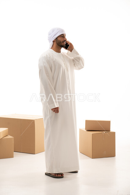 بورتريه لرجل عربي اماراتي خليجي يرتدي الزي الاماراتي , يعمل في توصيل الطلبات والبضائع للزبائن,  طلبات اونلاين, عملية شحن وتوصيل موثوقه,  توثيق الطلبات, تاكيد الحجوزات, اجراء مكالمات هاتفية , صورة الجسم بالطول الكامل , خلفية بيضاء .