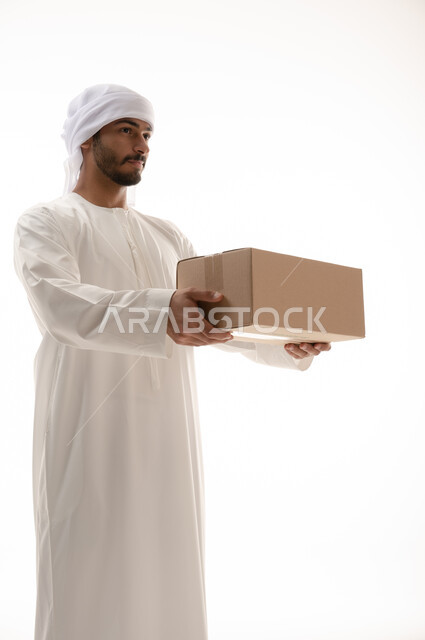 Portrait of an Arab Emirati Gulf man wearing Emirati dress, working in delivering orders and goods to customers, online shopping, online requests, reliable shipping and delivery, storekeeper, sales representative, documenting requests, confirming reservat