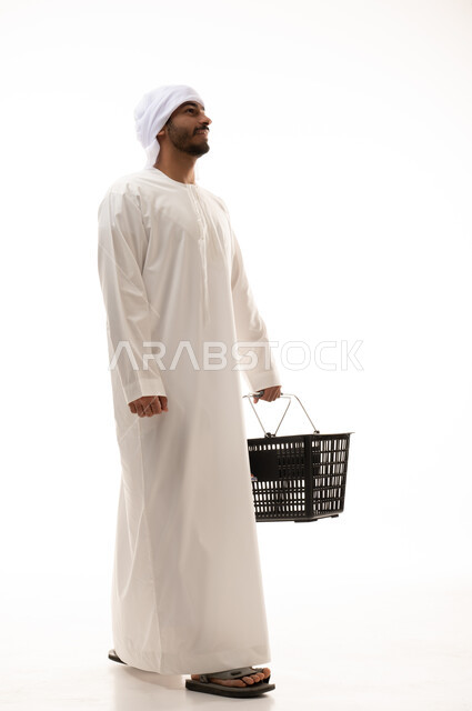  بورتريه لشاب اماراتي خليجي يرتدي الزي الاماراتي التقليدي يقوم بالتسوق ، سله مشتريات ، تعابير وجه مختلفة  ، شراء الاحتياجات المنزلية ، السلع والمواد الغذائية المختلفة ، مستلزمات المستهلك , صورة الجسم بالطول الكامل , خلفية بيضاء .