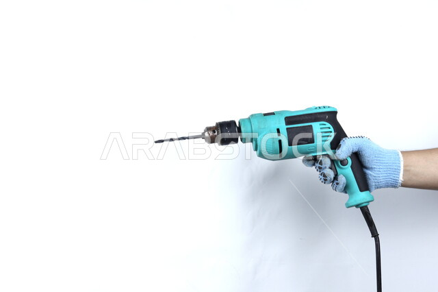 Close-up of a hand holding an electric drill, electrical repair tools and equipment, plastic handle, drilling and perforating, white background.