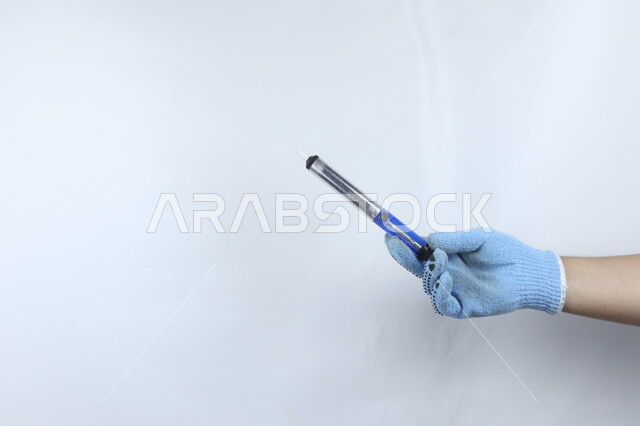 صورة مقربة ليد بالقفاز  تمسك قلم تخطيط مغطى  , خطة ملاحظة , تأشير وإعلان , لوح ابيض ,  خلفية بيضاء .