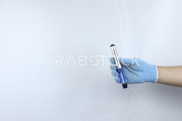 صورة مقربة ليد بالقفاز  تمسك قلم تخطيط مغطى  , خطة ملاحظة , تأشير وإعلان , لوح ابيض ,  خلفية بيضاء .