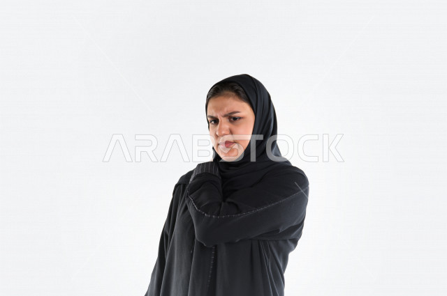 بورتريه لمرأه عربيه سعوديه خليجيه ترتدي العباءة والحجاب , إيماءات وجه ويدين تدل على الشعور  بألم في الكتف, الإحساس بالمرض, التعب والإرهاق, الحاجه للعلاج, طلب المساعده , خلفية بيضاء .